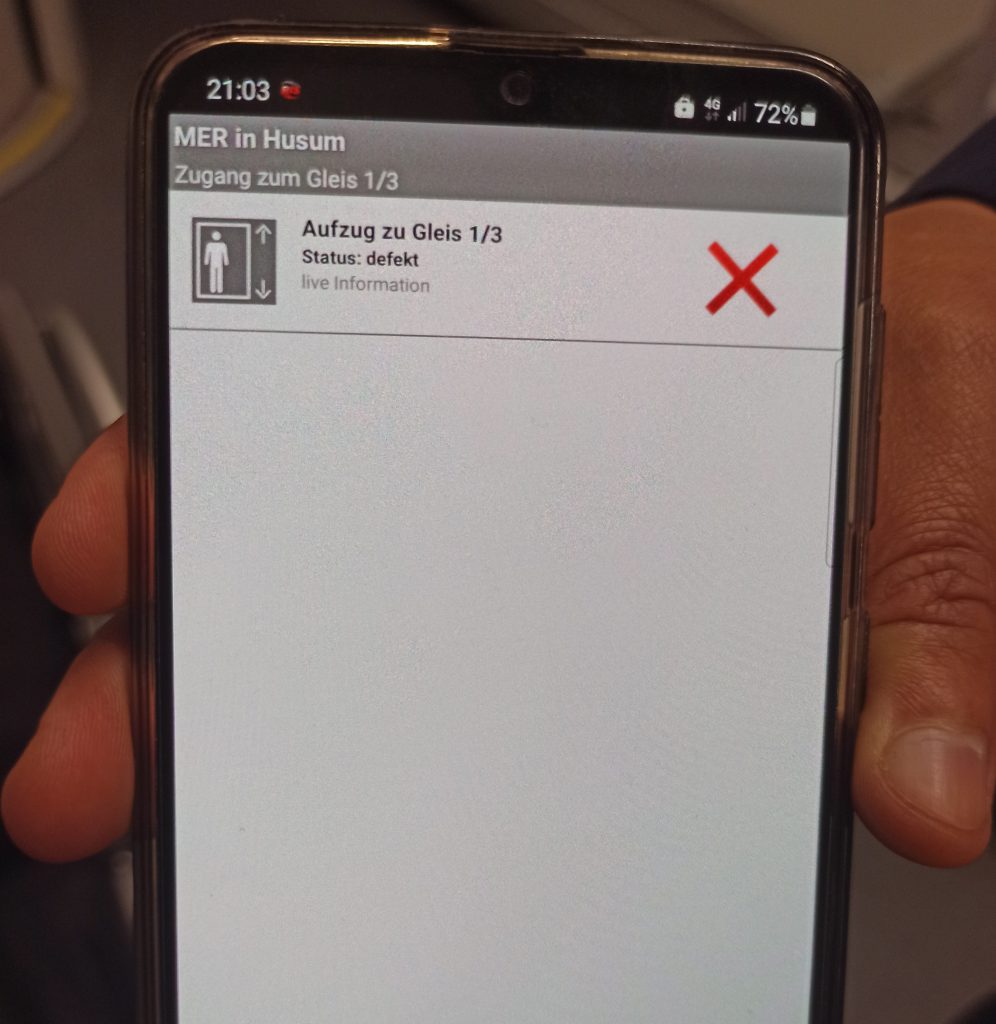 Bild zeigt Handy und Hand, die das Telefon hält. Auf dem Display ein Aufzug mit rotem Kreuz