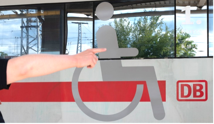 Hand zeigt auf großes Rollstuhlsymbol an einem ICE